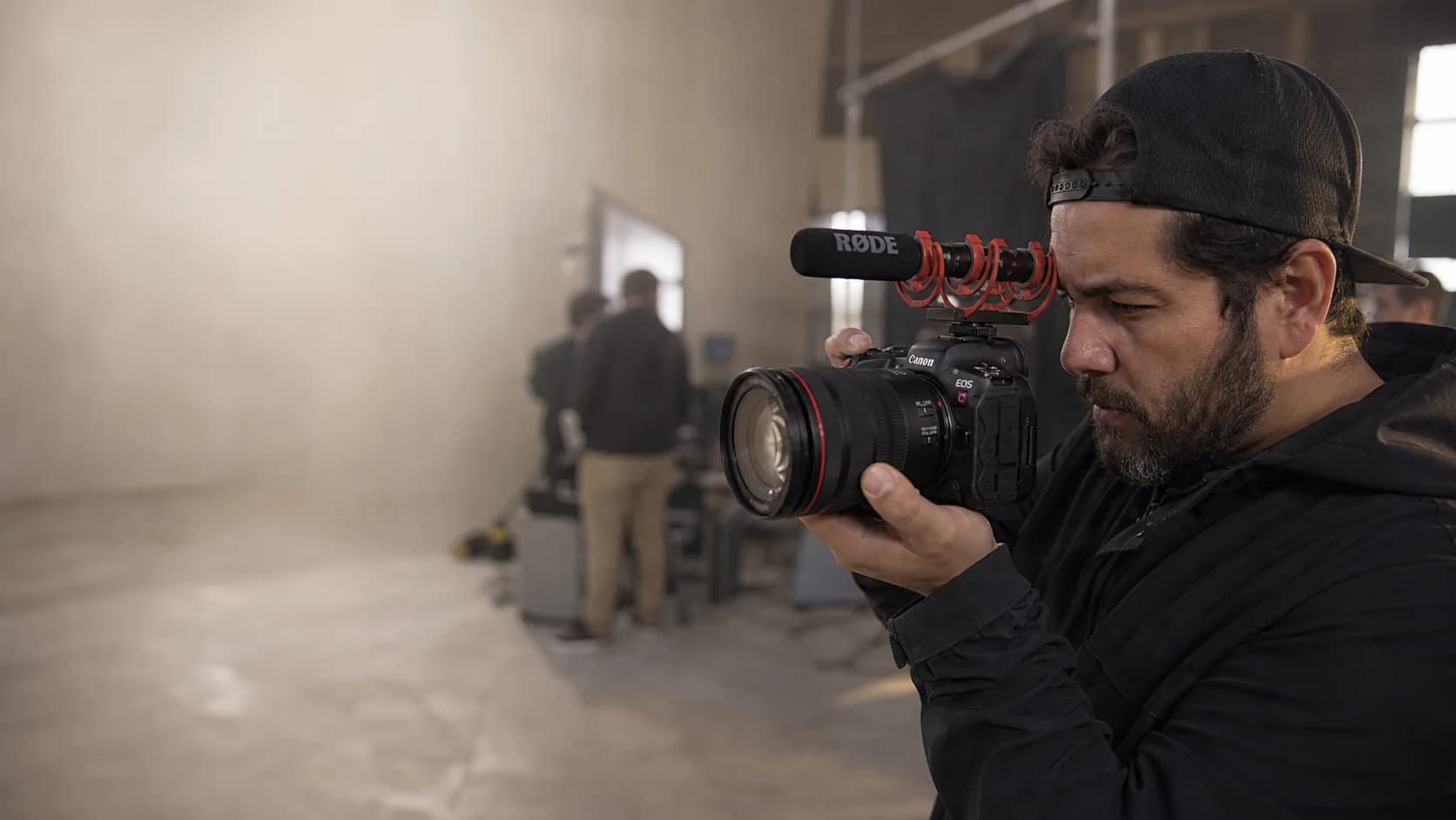 Filmmaker operando uma Canon EOS R5 C com lente RF e microfone Rode em um set